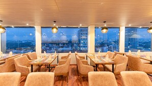 A restaurant with a city view, wooden ceiling, and modern pendant lighting. - Pearl Grand By Rathna (Colombo)