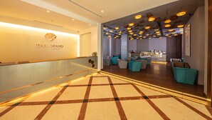 A hotel lobby with a check-in counter, seating area, and a patterned floor. - Pearl Grand By Rathna (Colombo)
