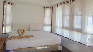 A hotel room with a bed, curtains, a ceiling fan, and a window. - Diamond Beach Resort (Koh Tao)