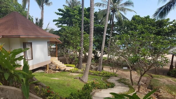 A small house with a red roof, surrounded by lush greenery and palm trees. - Diamond Beach Resort (Koh Tao)