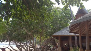 A beachside building with a covered patio area, surrounded by trees and a sandy beach. - Diamond Beach Resort (Koh Tao)