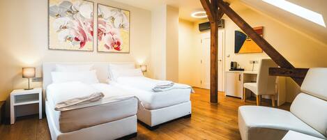 A modern bedroom with a double bed, a desk, and a chair, wooden flooring, and a skylight.