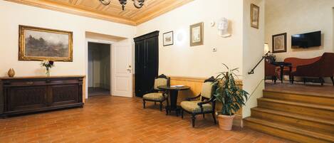 A spacious lobby with a high ceiling, a chandelier, a fireplace, and a staircase leading to another level.