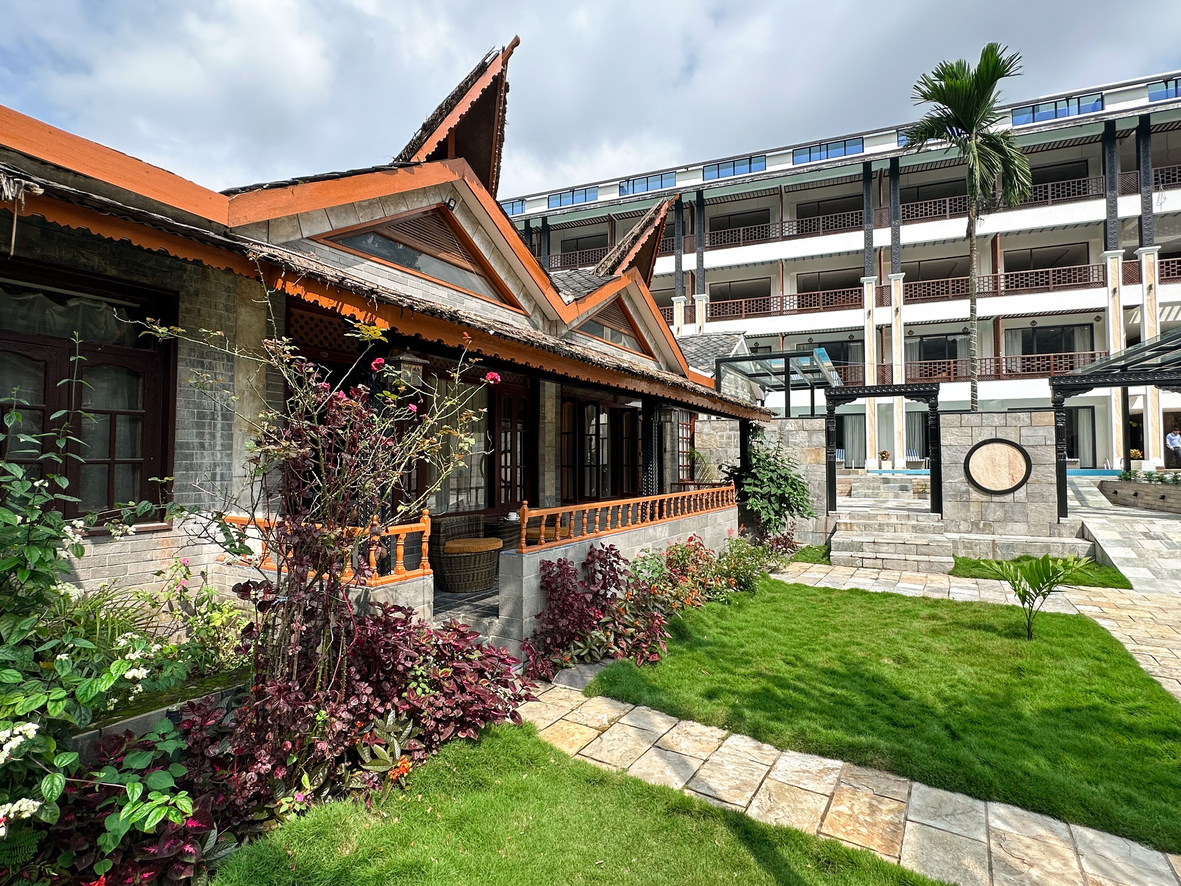 A traditional building with a tiled roof, a covered porch, and a stone wall with a circular emblem.