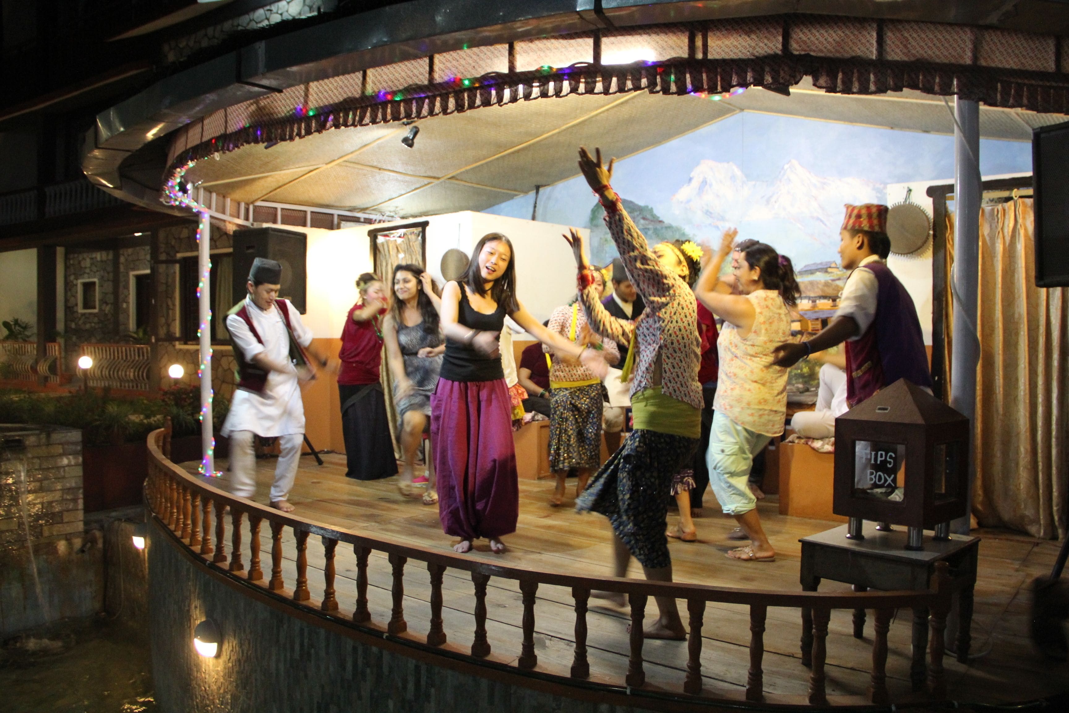 A stage with people performing, surrounded by a railing and a decorative fence.