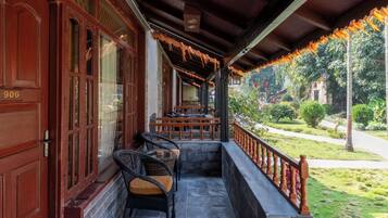 A covered porch with wicker furniture and a stone wall.