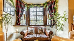 A cozy corner with a leather sofa, a wooden coffee table, and a window with curtains. - The Tormaukin Hotel (Dollar)