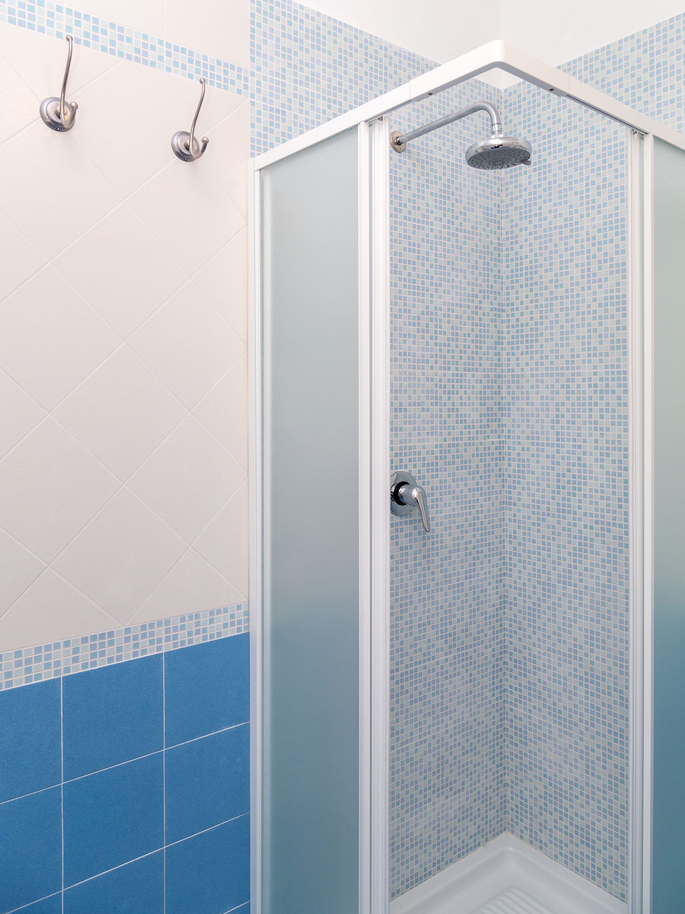 A shower with a glass door and a tiled wall.