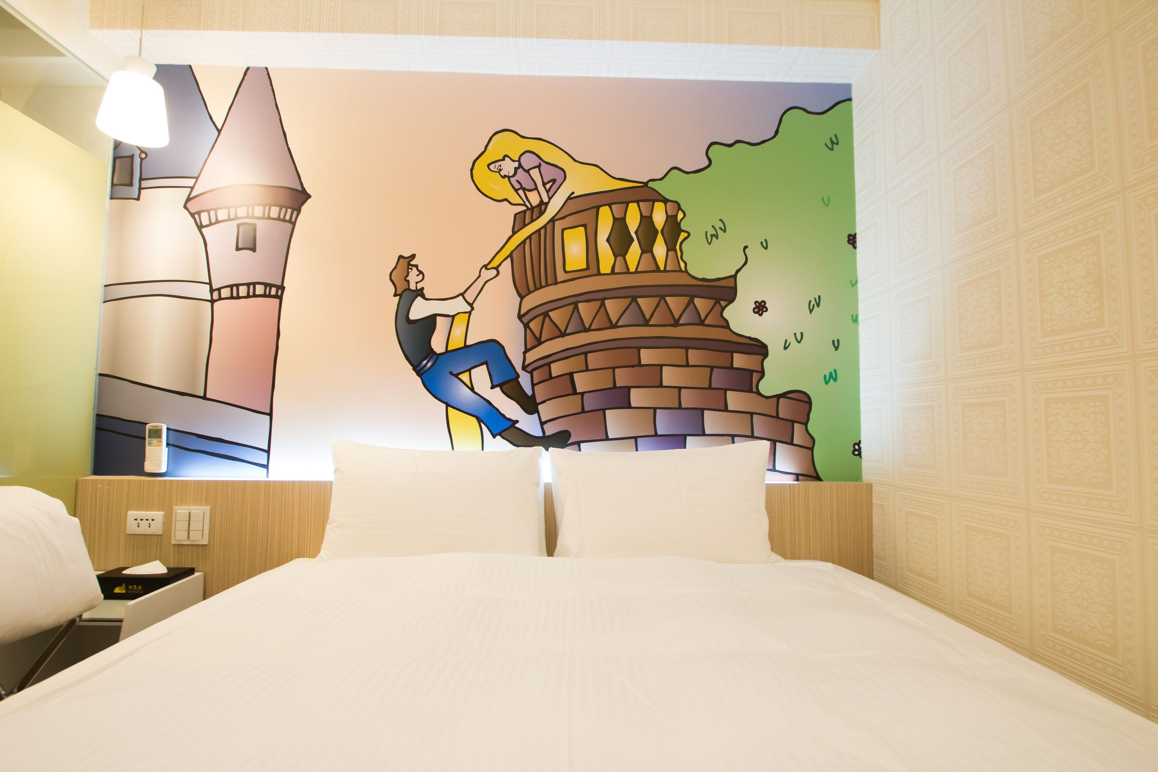 Une chambre d’hôtel avec un lit, une table de chevet, une lampe et une fresque représentant un château.