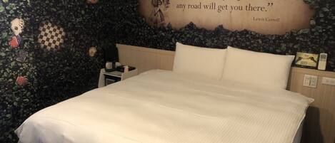 A bedroom with a bed, a nightstand, a wall with a quote, and a clock.