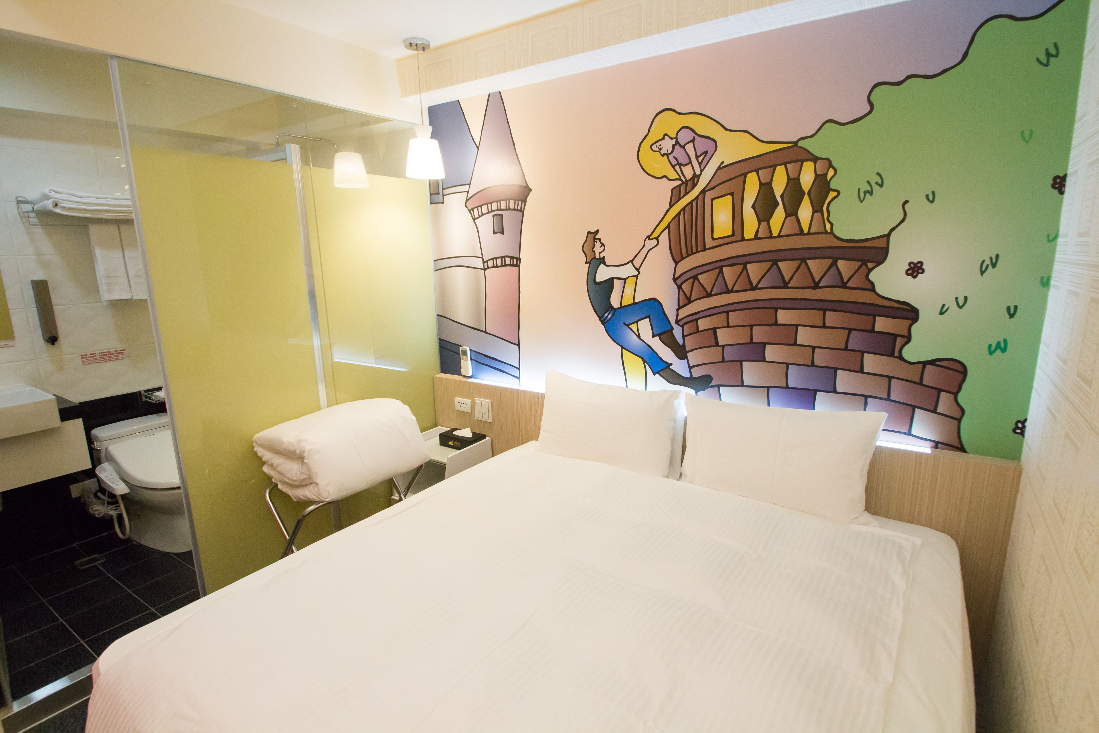 A hotel room with a bed, a bathroom, and a mural on the wall.