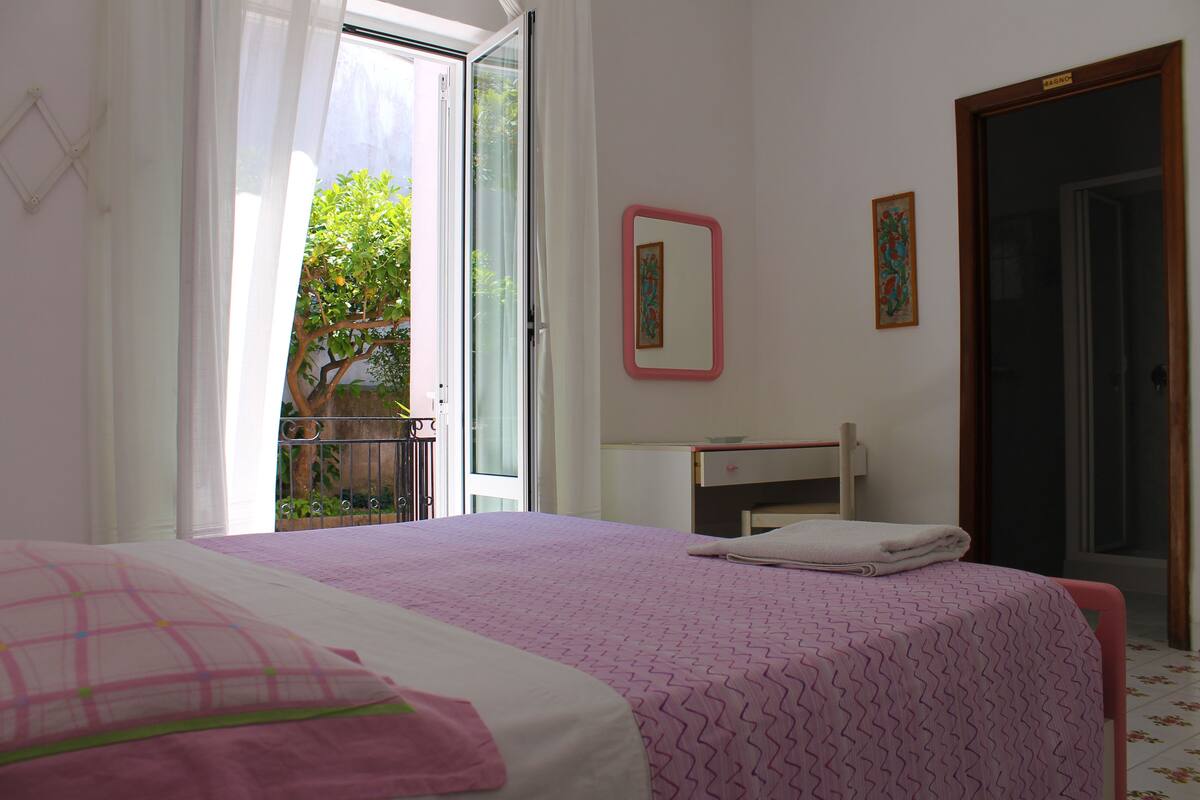 Un dormitorio con cama, mesita de noche, espejo y puerta.