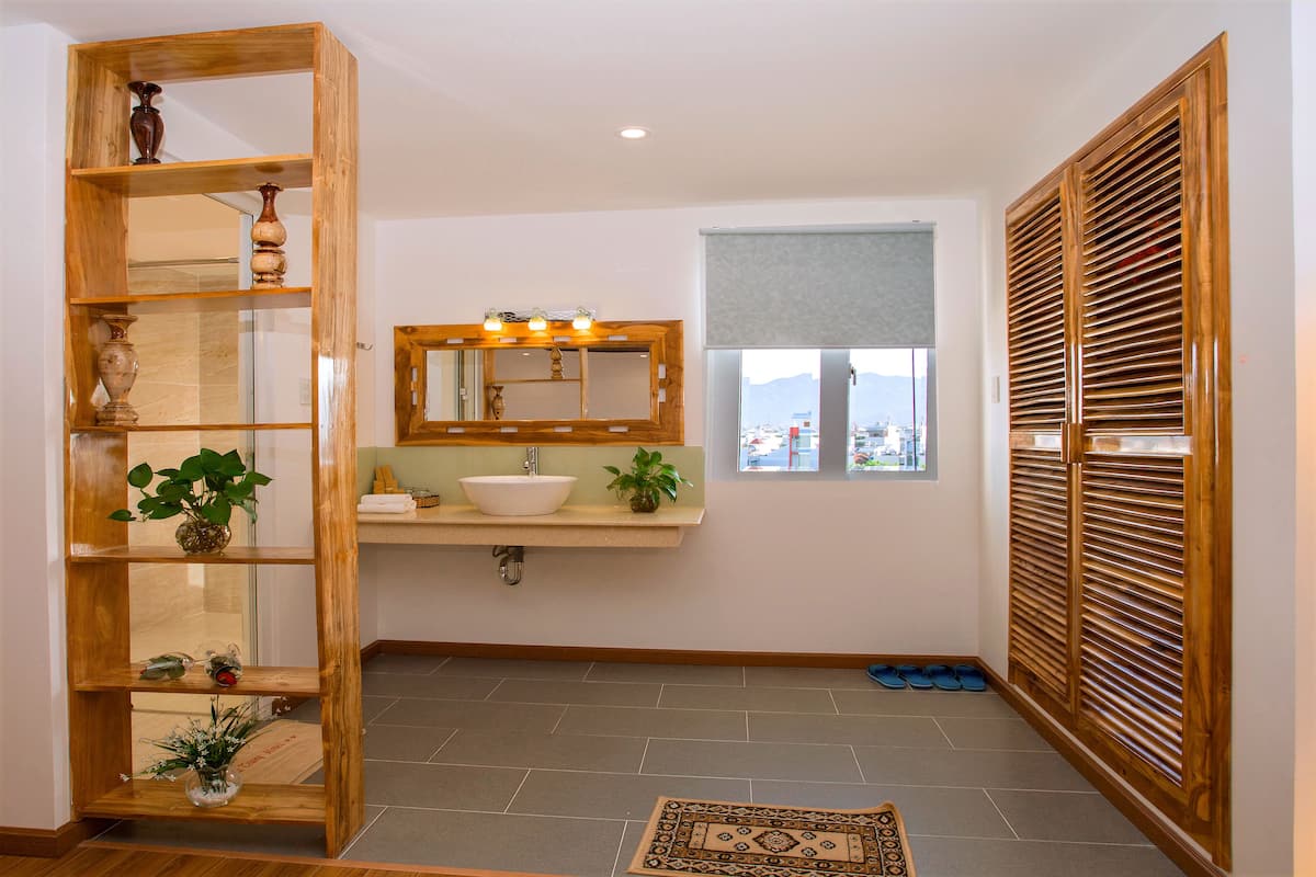 A bathroom with a wooden vanity, a sink, a mirror, and a window with a view.