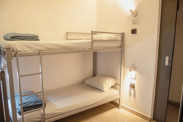 A bunk bed room with a lower bunk, a ladder, a folded blanket, and a wall-mounted light fixture. - Soul Hostel (São Paulo)