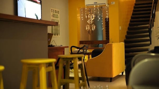 Una sala de estar moderna con un sofá, sillas amarillas, un televisor y un equipo de aire acondicionado.