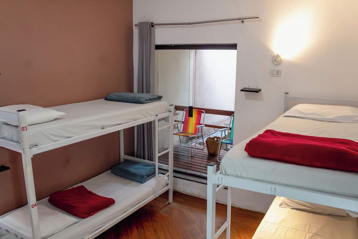 Un dormitorio con literas, una ventana con vistas, una silla y una mesita.