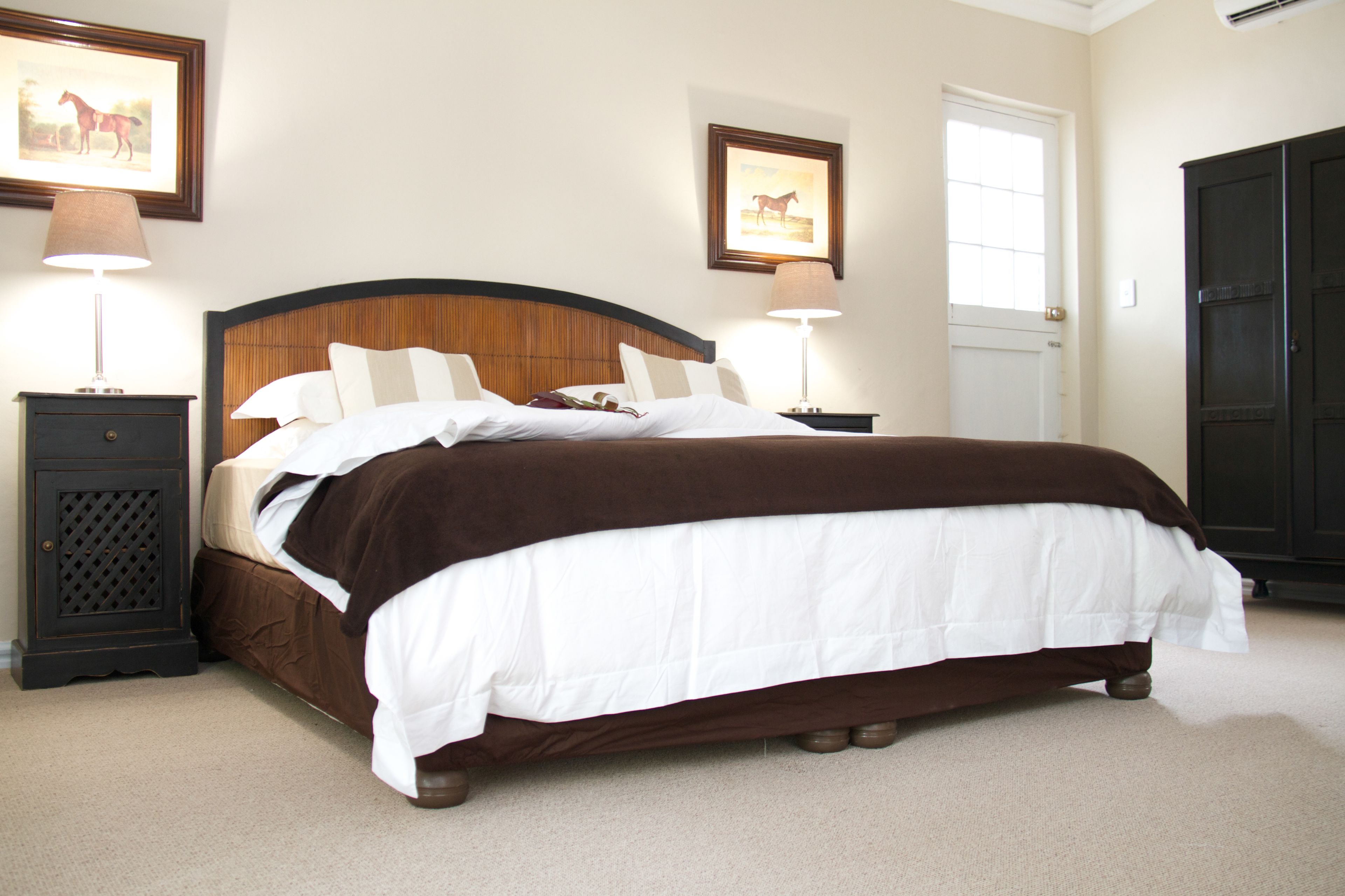 A neatly made bed with a wooden headboard, two bedside tables with lamps, and framed artwork on the walls.