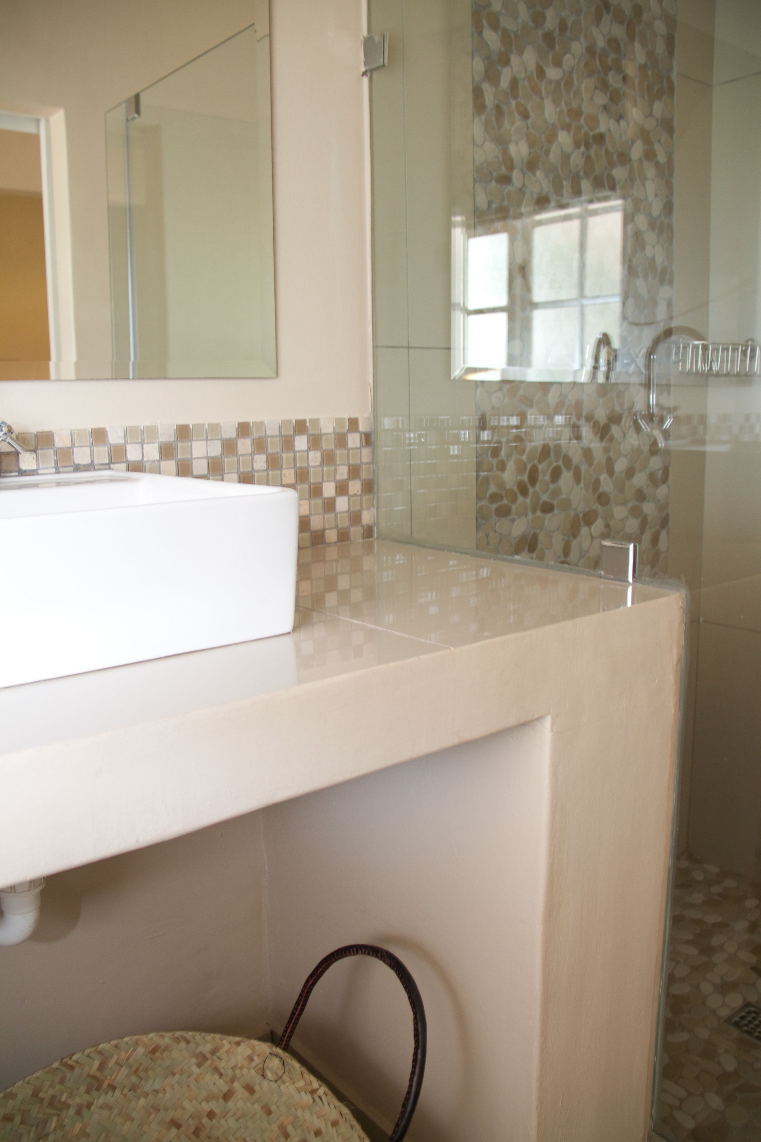 Un baño con lavamanos blanco, un espejo y zona de ducha.