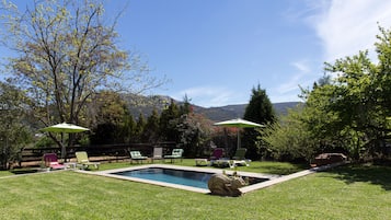 Una piscina al aire libre, sombrillas, sillones reclinables de piscina