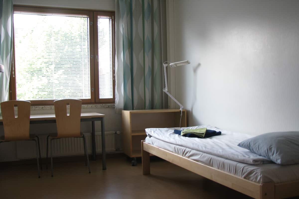 Una habitación con una cama individual, un escritorio y una silla.