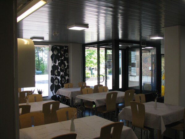Un restaurante con varias mesas y sillas, amplias ventanas y una decoración interior moderna.