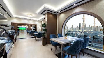 A modern dining area with a view of a city skyline, including a mosque.