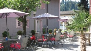 Un patio al aire libre con mesas, sillas, sombrillas y plantas en macetas.