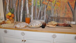 A breakfast buffet with various food items and a painting of trees in the background. - Affittacamere Rubino (Ponte nelle Alpi)