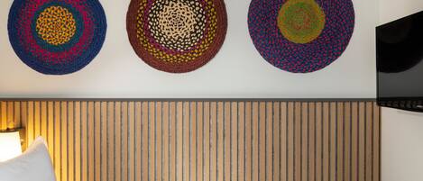 A hotel room with a bed, a wall-mounted TV, and three circular wall art pieces.
