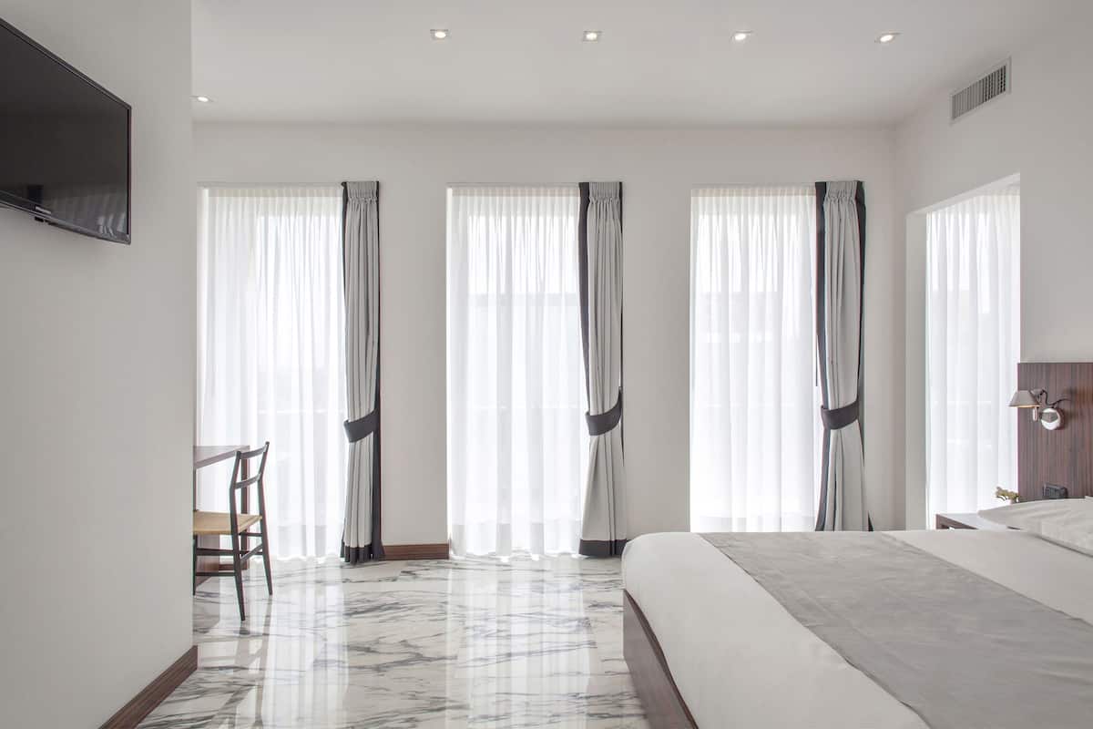 A modern hotel room with a large bed, a desk, and a chair.