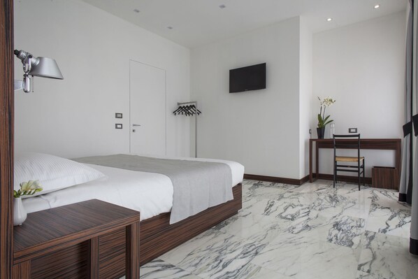 A modern hotel room with a bed, a desk, a chair, a TV, and a bathroom. - My Bed Montenapoleone (Milan)