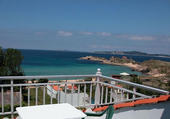 A balcony with a view of the sea, a white table, and green chairs. - Hotel Estrella del Mar (Sanxenxo)