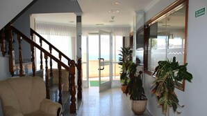 A lobby with a wooden staircase, a beige sofa, and potted plants.