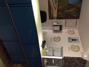 Une pièce avec un meuble bleu, un meuble en verre contenant une sculpture, et trois horloges accrochées au mur.