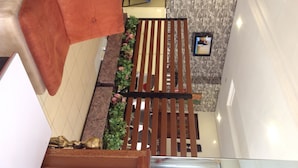 Un espace intérieur comprenant un banc en bois, un canapé rouge et une petite composition florale.