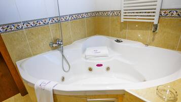 Un baño con una bañera blanca, ducha y un perchero para toallas.