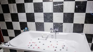 Een badkamer met een zwart-wit betegelde wand, een wit bad en een gestreepte vloer.