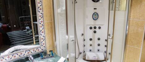 A modern bathroom with a glass-enclosed shower, a marble sink, and a large mirror with a decorative frame.