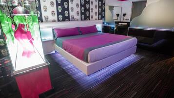 Quarto de hotel moderno com uma cama grande, uma escrivaninha com computador e uma penteadeira com espelho.
