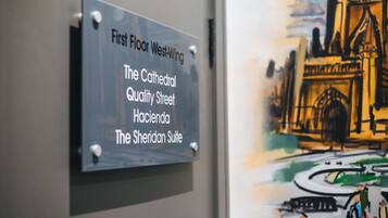 A sign with room names: First Floor West-Wing, The Cathedral Quality Street, Hacienda, The Sheridan Suite.