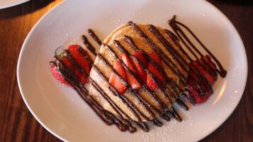 A plate with pancakes topped with strawberries and chocolate syrup.