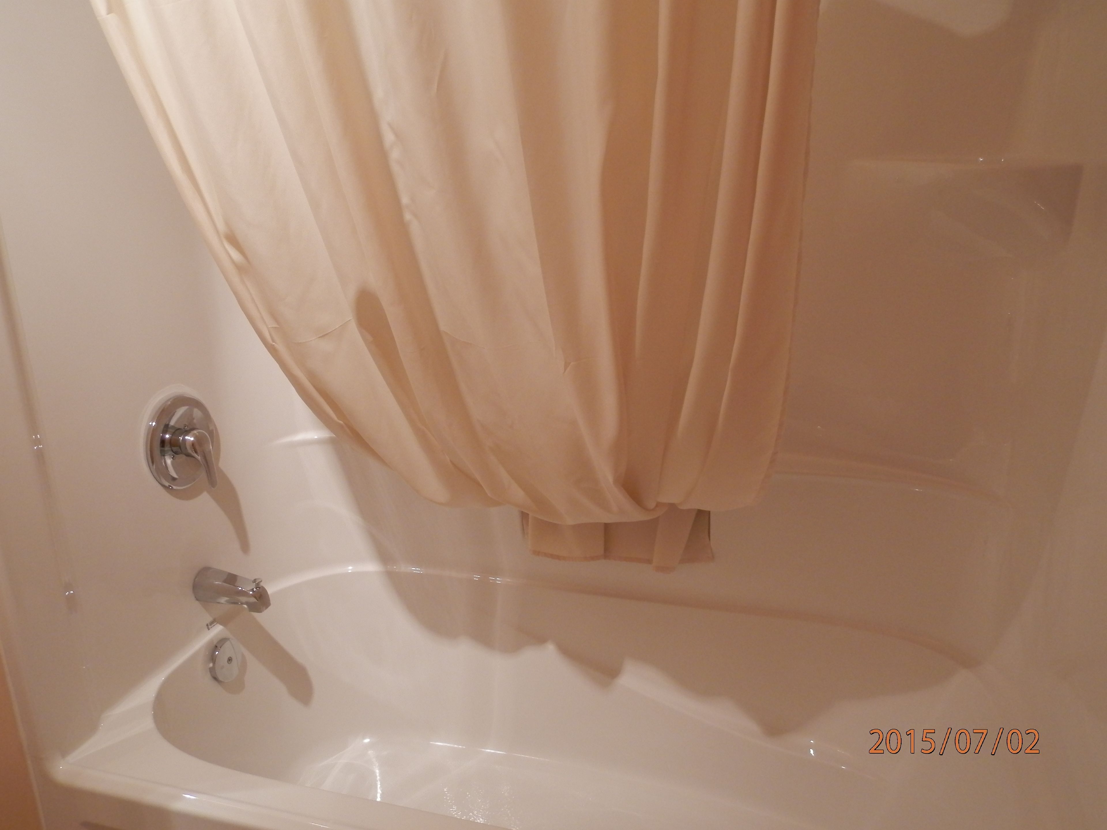 A bathroom with a bathtub, a faucet, and a shower curtain.