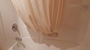 A bathroom with a bathtub, a faucet, and a shower curtain.