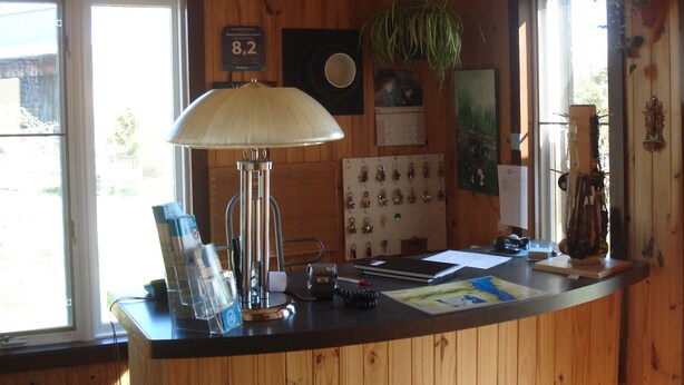 Ein Holzinnenraum mit Schreibtisch, Lampe, Schlüsseln, Kalender und Pflanze.