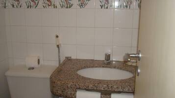 Un baño con inodoro, lavamanos y perchero para toallas.