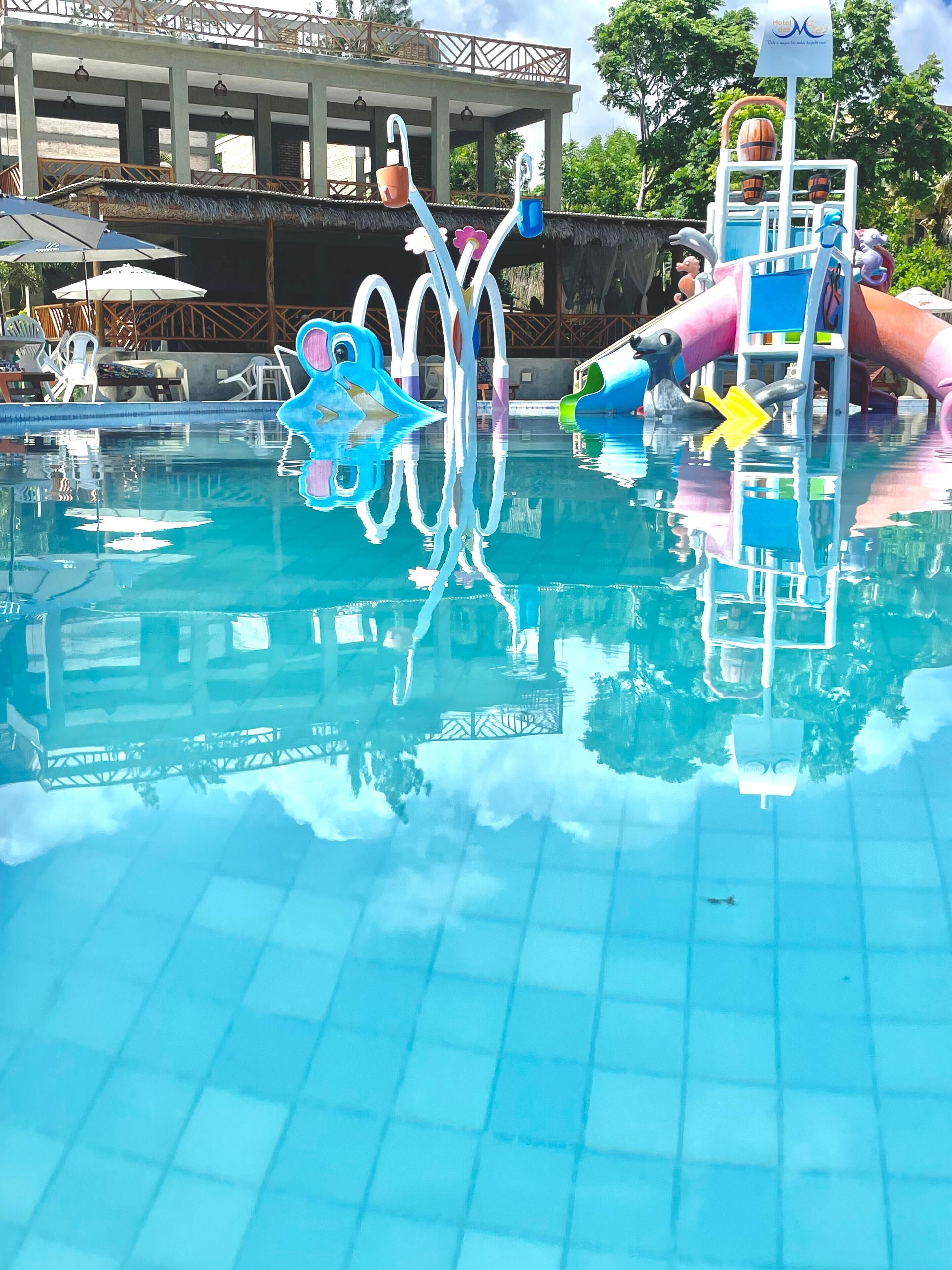 Una piscina con tobogán y una estructura con forma de delfín.