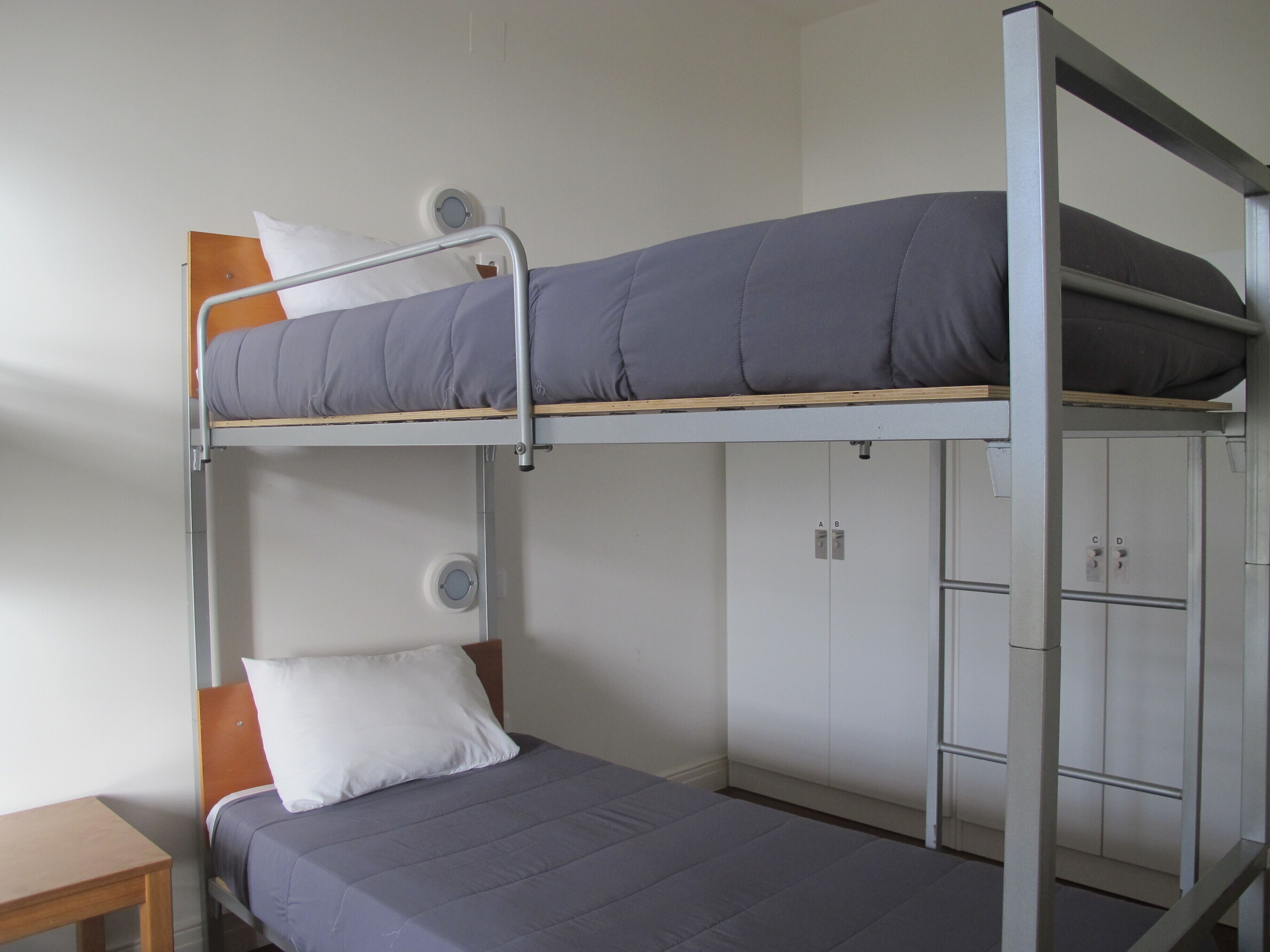 A bunk bed room with a desk and cabinets.