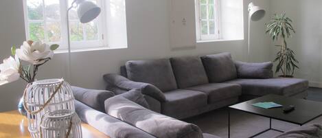 A modern living room with a grey sectional sofa, a wooden coffee table, and a white floor lamp.
