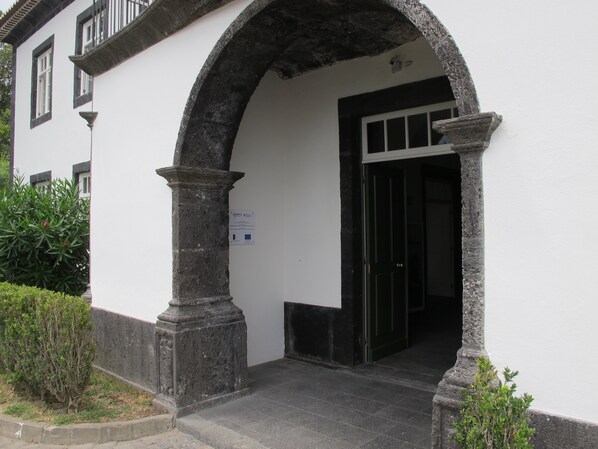Una entrada de edificio con un arco de piedra, una puerta y un cartel en la pared.
