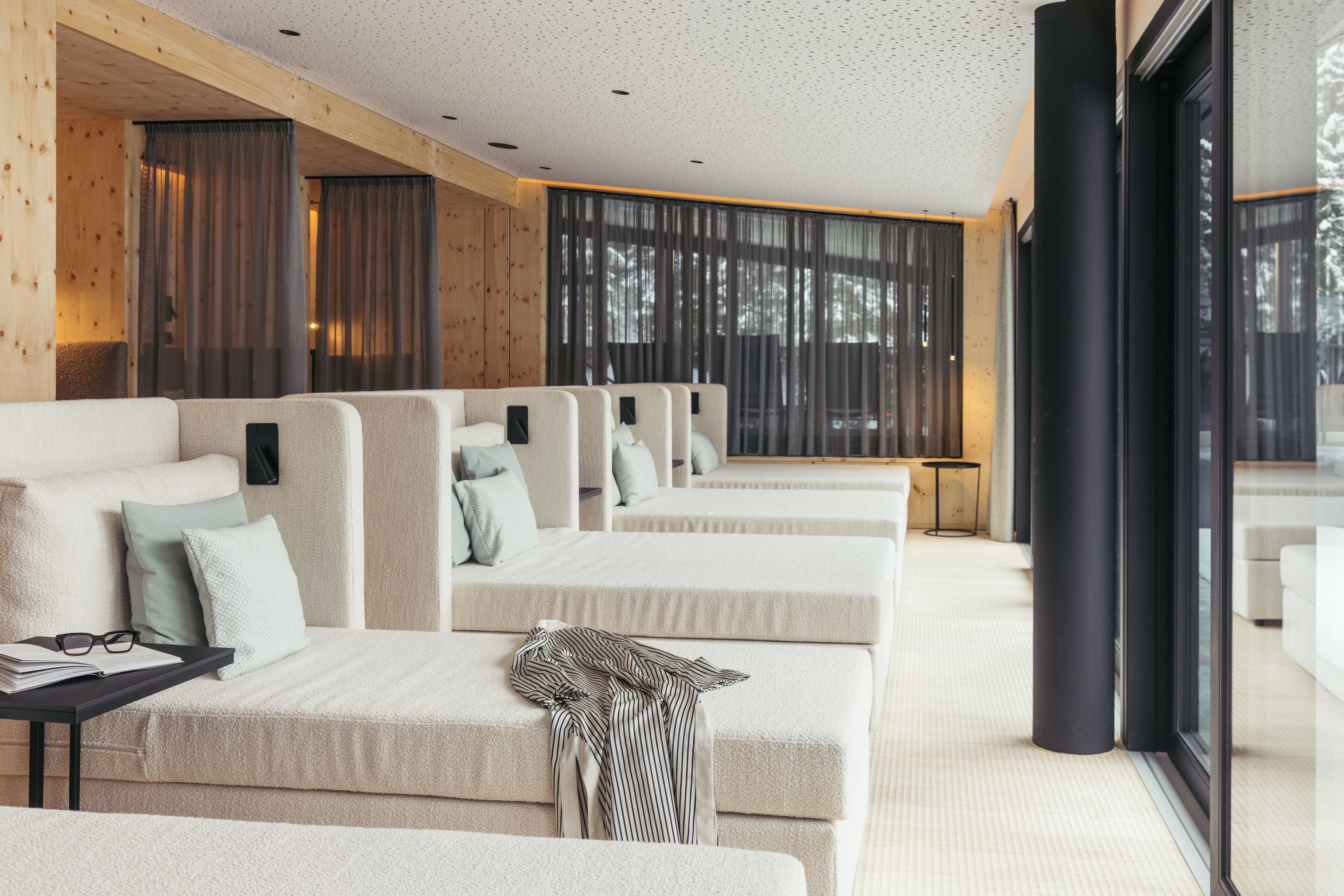 Una habitación de hotel moderna con un ventanal grande, un sofá, una pequeña mesa y una cama.